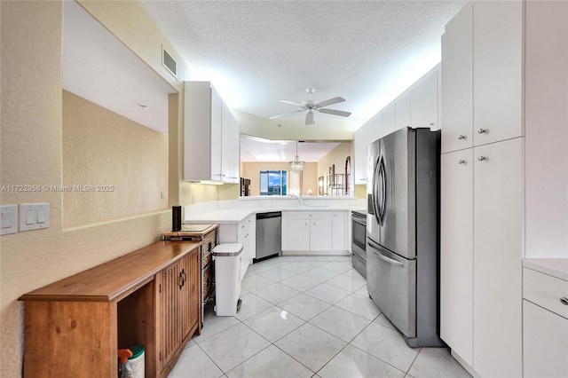 kitchen featuring kitchen peninsula, appliances with stainless steel finishes, a textured ceiling, ceiling fan, and white cabinets