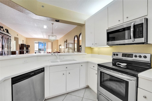 kitchen featuring appliances with stainless steel finishes, white cabinetry, a notable chandelier, and sink