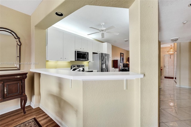 kitchen with ceiling fan, kitchen peninsula, a breakfast bar area, white cabinets, and appliances with stainless steel finishes