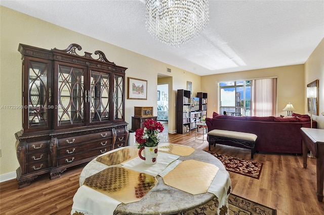 dining space with hardwood / wood-style floors, a textured ceiling, and an inviting chandelier