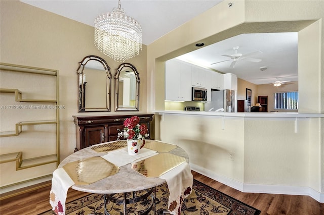 dining area with ceiling fan with notable chandelier and dark hardwood / wood-style flooring