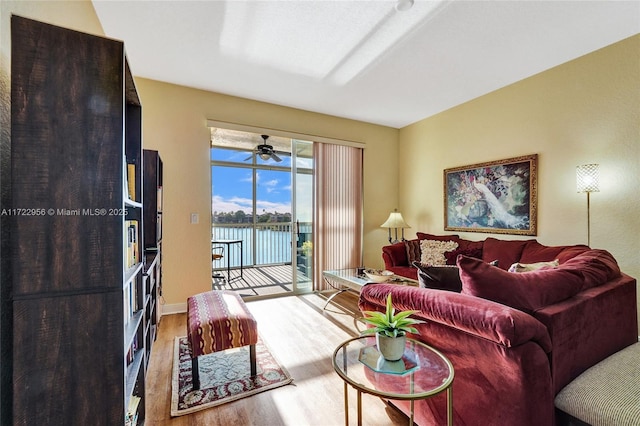 living room featuring a water view, ceiling fan, and light hardwood / wood-style floors