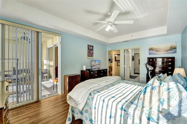 bedroom featuring access to exterior, hardwood / wood-style floors, a raised ceiling, and ceiling fan