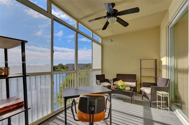 sunroom with a water view and ceiling fan