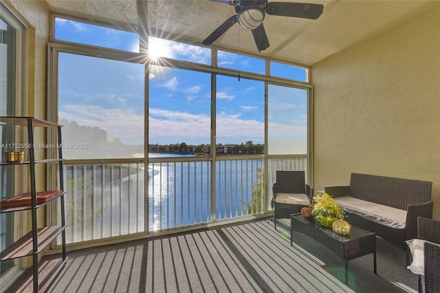 sunroom with a wealth of natural light, a water view, and ceiling fan