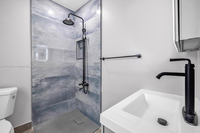 bathroom with a tile shower, sink, and toilet