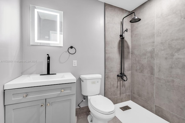 bathroom with tiled shower, vanity, and toilet