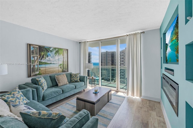 living room with a textured ceiling, light wood-type flooring, and floor to ceiling windows