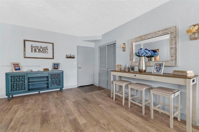 interior space featuring a textured ceiling, wood finished floors, and baseboards