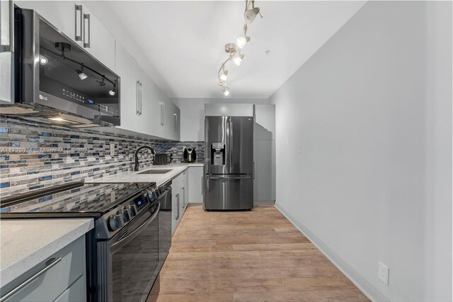 kitchen with gray cabinetry, sink, stainless steel appliances, and light hardwood / wood-style flooring