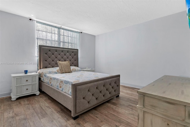 bedroom featuring a textured ceiling, wood finished floors, and baseboards