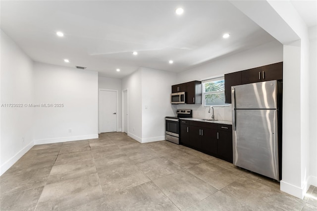 kitchen with appliances with stainless steel finishes, dark brown cabinets, and sink