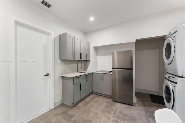 washroom featuring stacked washer and dryer and sink