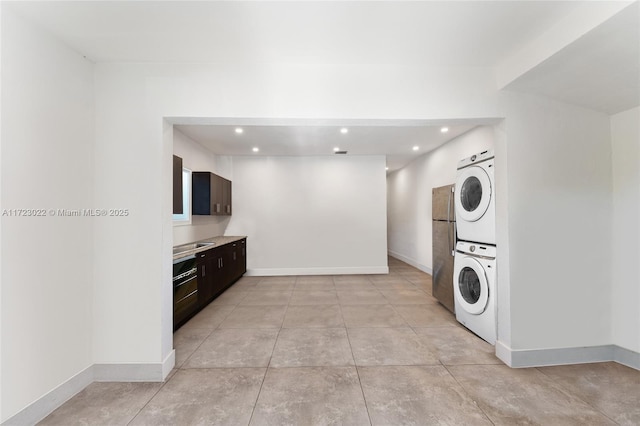 kitchen featuring stacked washer / drying machine, dark brown cabinetry, and stainless steel refrigerator