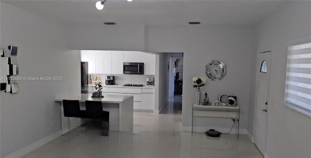 kitchen with kitchen peninsula, a breakfast bar, white cabinetry, and black appliances