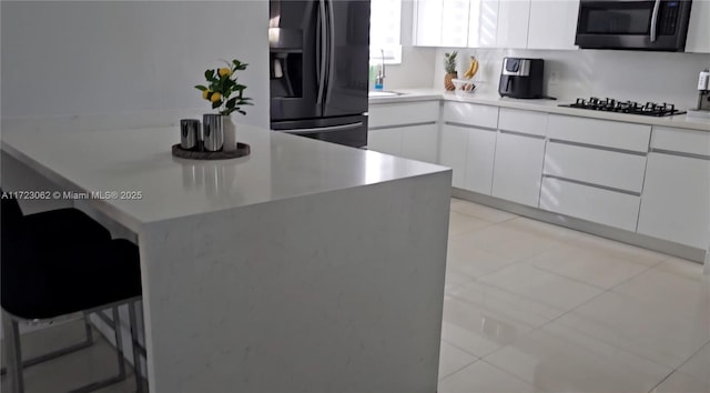 kitchen with black appliances, white cabinetry, sink, and light tile patterned floors