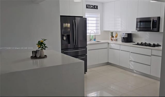 kitchen featuring white cabinetry, sink, gas stovetop, refrigerator with ice dispenser, and light tile patterned floors