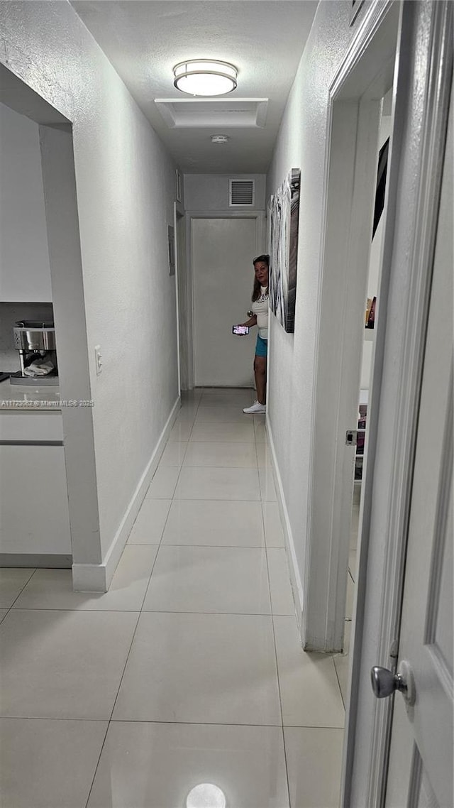 corridor featuring light tile patterned floors and a textured ceiling