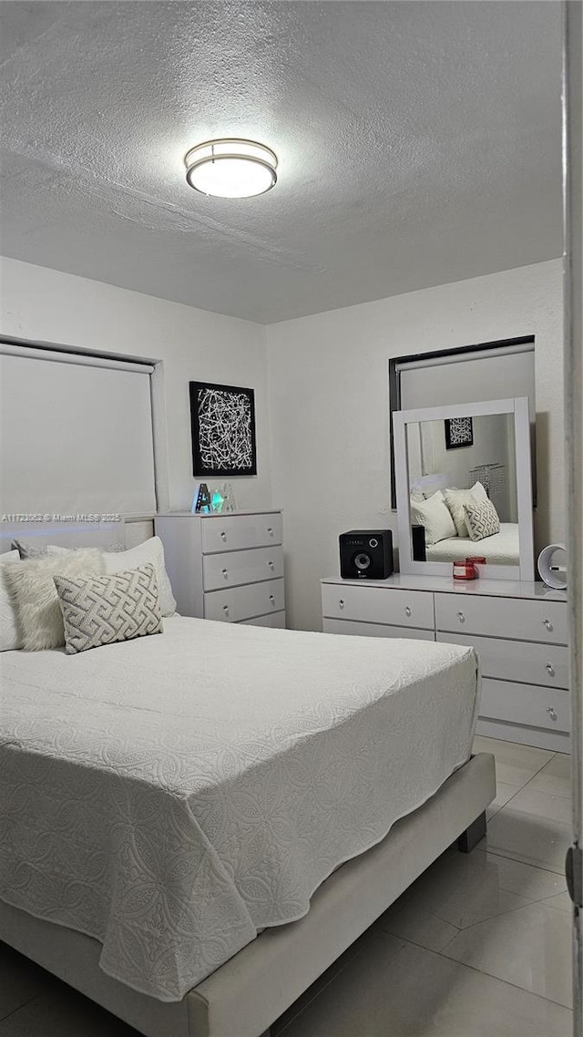 bedroom with a textured ceiling and tile patterned floors