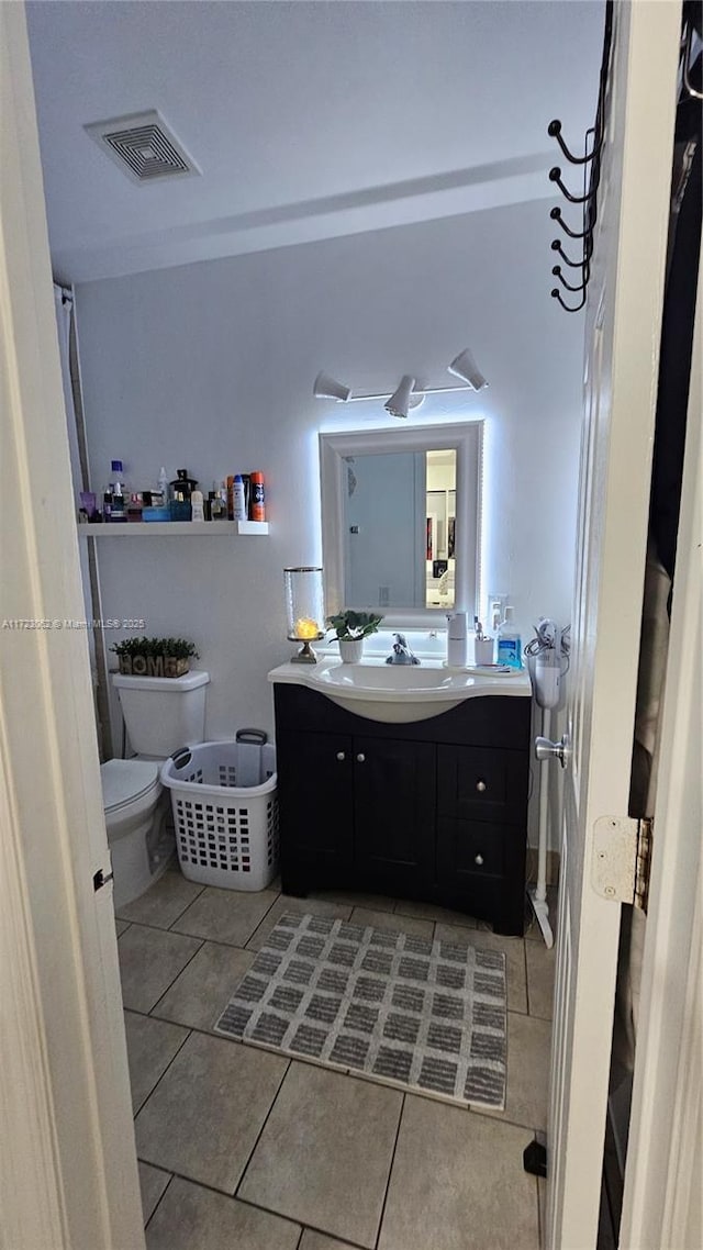 bathroom with toilet, vanity, and tile patterned floors