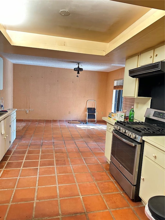 kitchen featuring cream cabinets, light tile patterned floors, and stainless steel range with gas stovetop