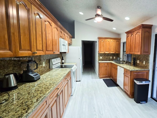 kitchen featuring lofted ceiling, white appliances, sink, ceiling fan, and light hardwood / wood-style floors