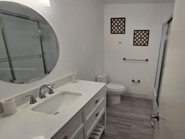 bathroom featuring toilet, vanity, wood-type flooring, and walk in shower