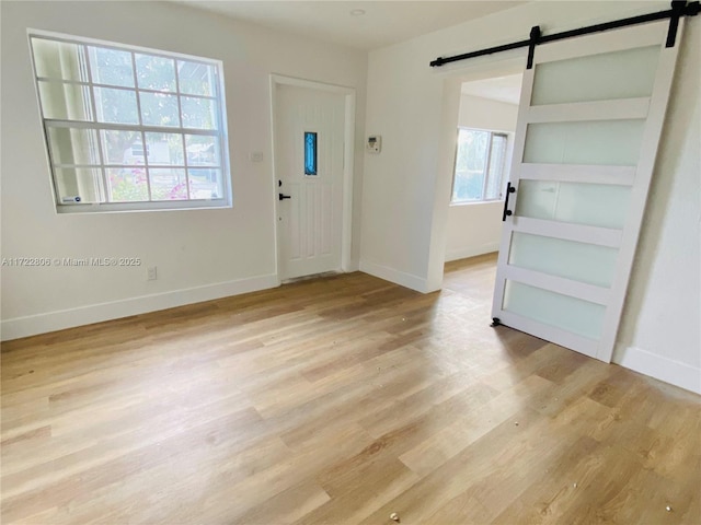 foyer entrance with light wood-type flooring and a barn door