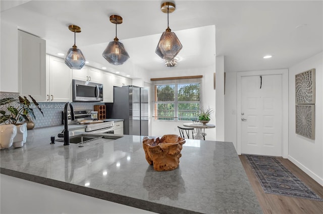 kitchen featuring decorative light fixtures, dark stone countertops, white cabinetry, and stainless steel appliances