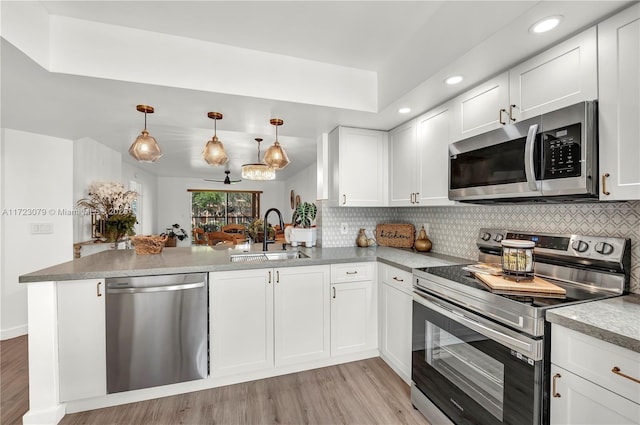 kitchen with sink, hanging light fixtures, stainless steel appliances, kitchen peninsula, and white cabinets