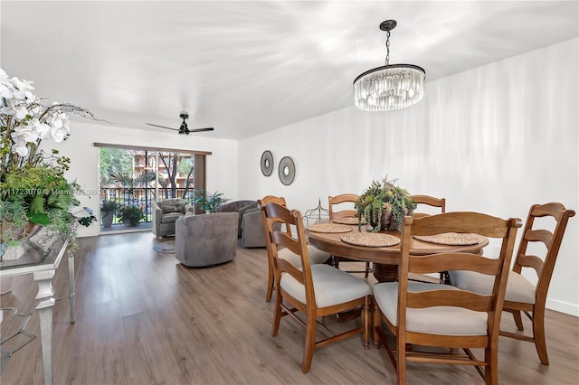 dining room featuring ceiling fan with notable chandelier and wood-type flooring