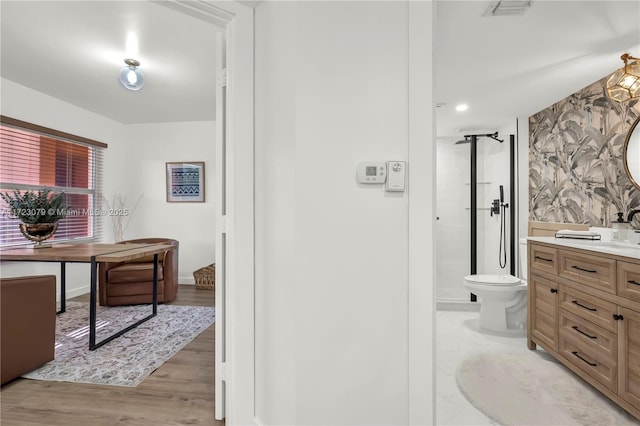 bathroom with a shower, wood-type flooring, vanity, and toilet