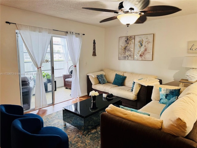 living room featuring ceiling fan, hardwood / wood-style floors, and a textured ceiling