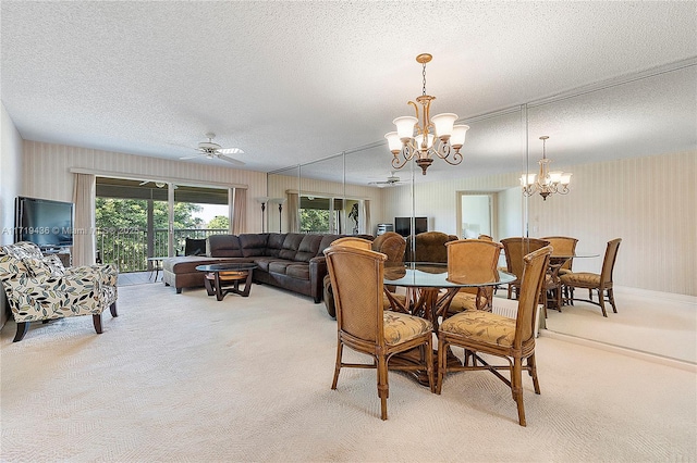 carpeted dining space featuring a textured ceiling and ceiling fan with notable chandelier