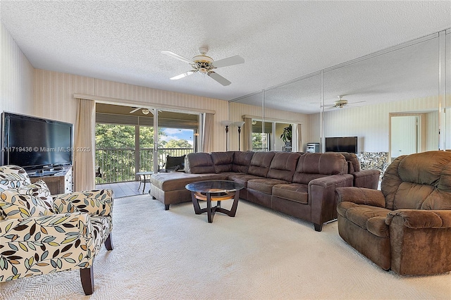 living room featuring ceiling fan, light colored carpet, and a textured ceiling