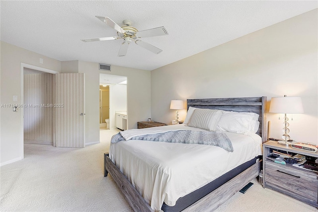 bedroom with ensuite bath, ceiling fan, light carpet, and a textured ceiling