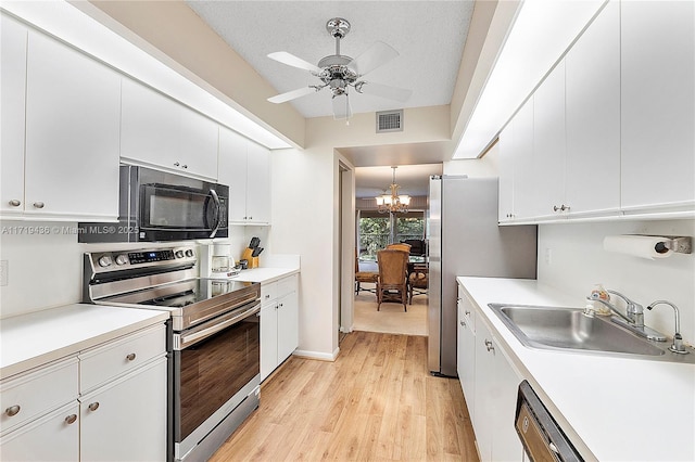 kitchen with appliances with stainless steel finishes, ceiling fan with notable chandelier, a textured ceiling, sink, and white cabinetry