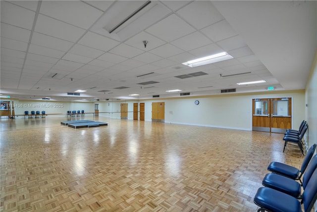 exercise room featuring a paneled ceiling and light parquet floors