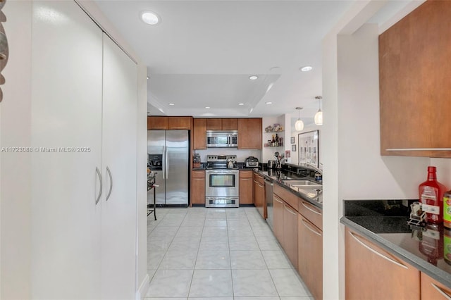 kitchen featuring dark stone counters, sink, hanging light fixtures, light tile patterned floors, and appliances with stainless steel finishes