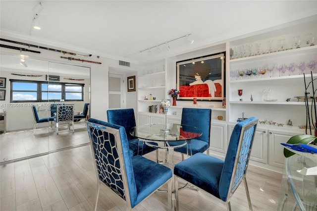 dining space with light hardwood / wood-style flooring and ornamental molding