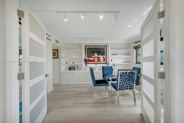 dining area featuring built in features, light hardwood / wood-style flooring, and a textured ceiling