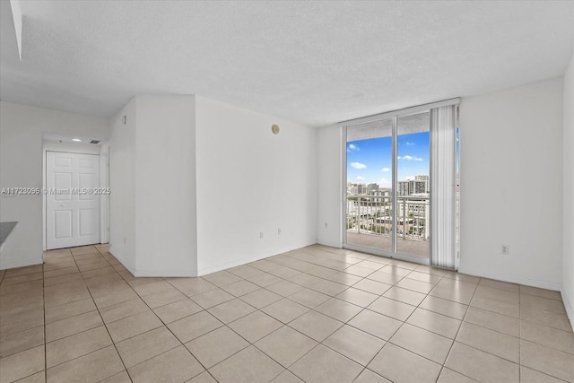 tiled spare room featuring floor to ceiling windows and a textured ceiling