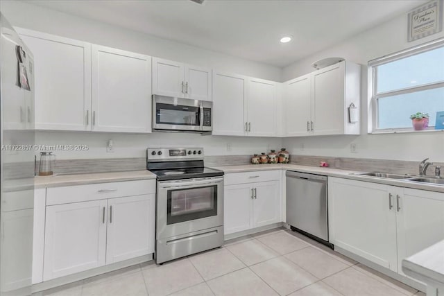 kitchen with light tile patterned floors, stainless steel appliances, and white cabinetry