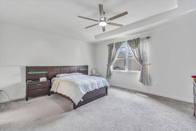 bedroom with a raised ceiling, ceiling fan, and light carpet