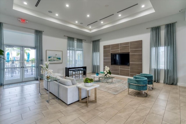 living room with a raised ceiling and french doors