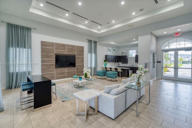 living room featuring a raised ceiling and french doors