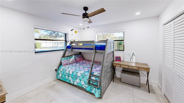 tiled bedroom featuring ceiling fan and a closet