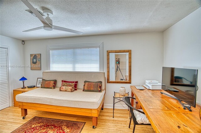 bedroom with a textured ceiling, ceiling fan, and light wood-style floors