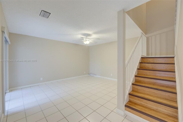 empty room featuring ceiling fan, light tile patterned floors, and a textured ceiling