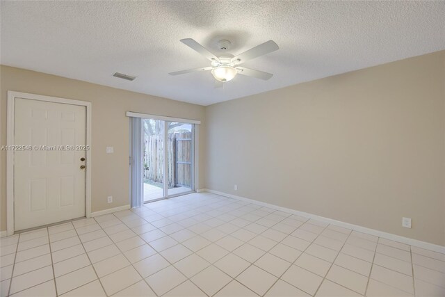 tiled spare room with ceiling fan and a textured ceiling